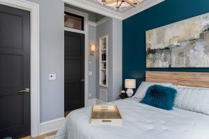 Bedroom with a teal accent wall, an abstract painting and a reclaimed wood headboard
