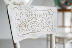 Close-up of an ornate vintage chair back with detailed carvings, captured in natural indoor light.