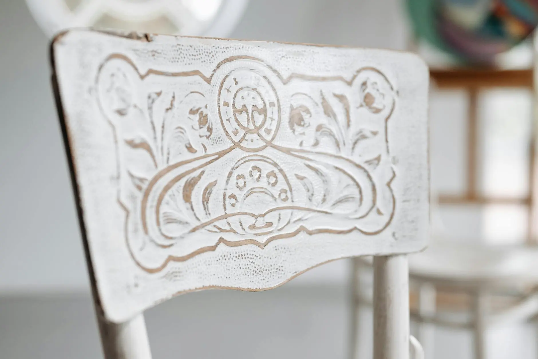 Close-up of an ornate vintage chair back with detailed carvings, captured in natural indoor light.