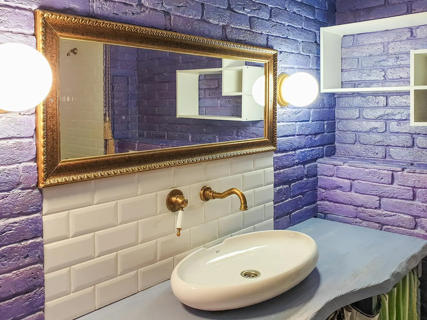 Stylish bathroom featuring purple brick walls, a golden faucet, and elegant vanity mirror.
